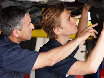 Auto shop owner trains new mechanic, providing the benefits of training to employees
