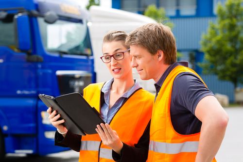 two trucking safety professionals review materials on a tablet