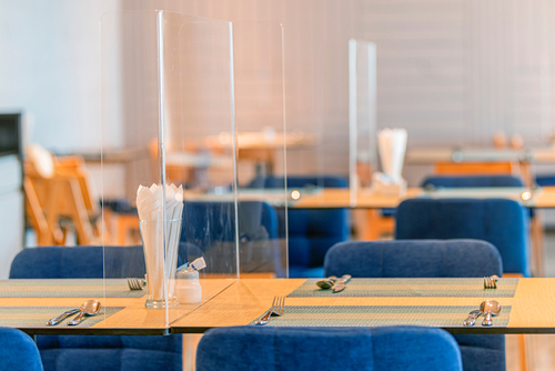 Social distancing at Restaurant. Seat for customers sitting separated in restaurant with table shield plastic partition to protect infection from coronavirus covid-19 