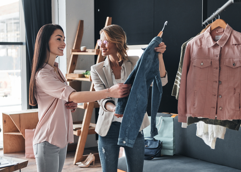 What do you think about this one? Beautiful young woman helping to choose clothes to her customer while working in the fashion boutique