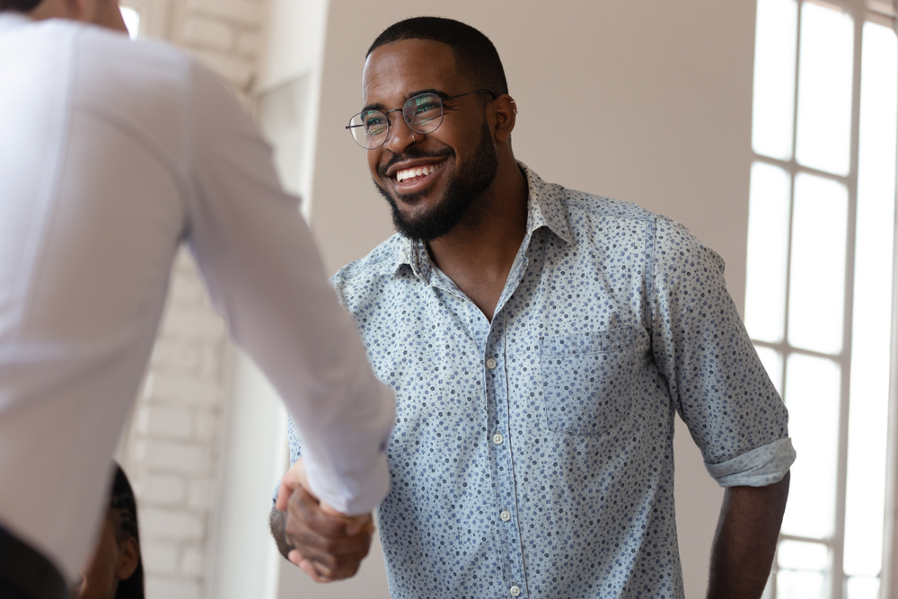 Head shot image joyful african american millennial worker shaking hands with colleague. Confident business partners making agreement before contract signing. Happy teammate thanking for help with job.