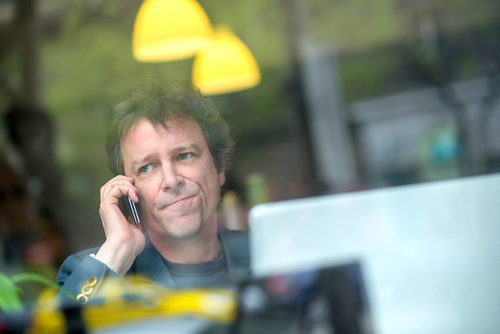 Portrait of a middle age businessman siting in the window of a coffee shop and speaking on the phone