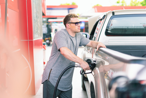 White caucasian car owner looks vacant while filling high energy power fuel into auto car tank in petrol station, commercial service for benzine, diesel, gasohol, gasoline.